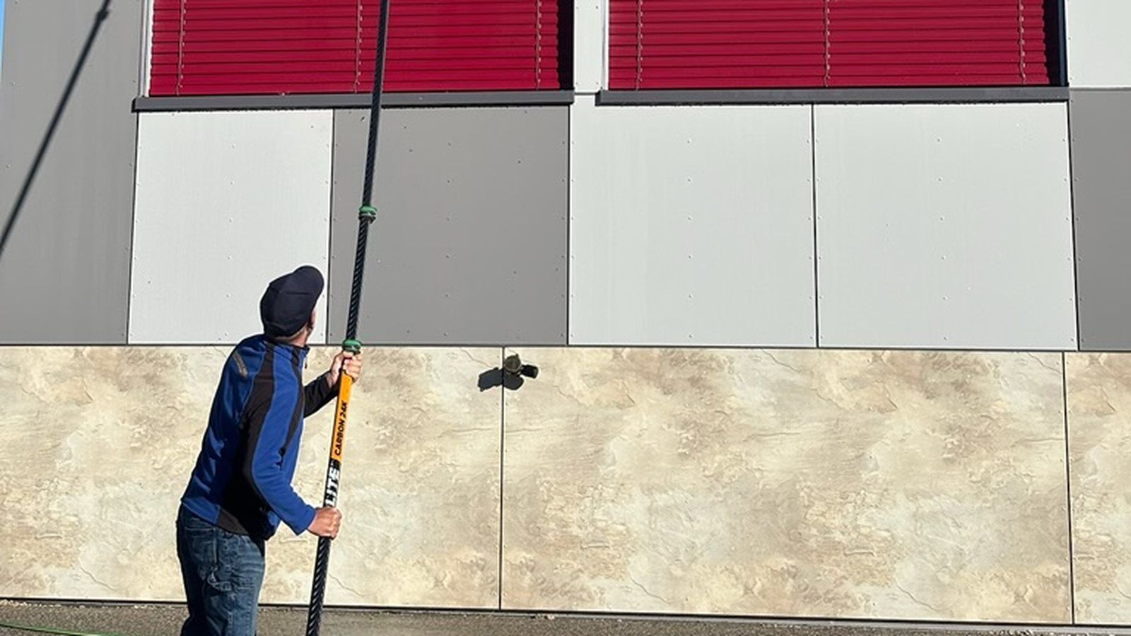 Un collaborateur de David Dougoud Services nettoie une façade vitrée à la perche